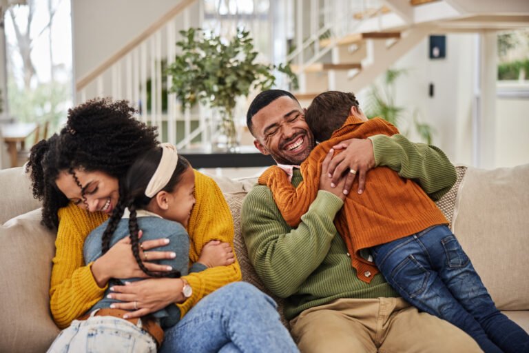 Happy, parents and kids with hug on sofa for appreciation, gratitude and safety in family at home. Mother, father and smile with affection of children in living room for connection, support and love