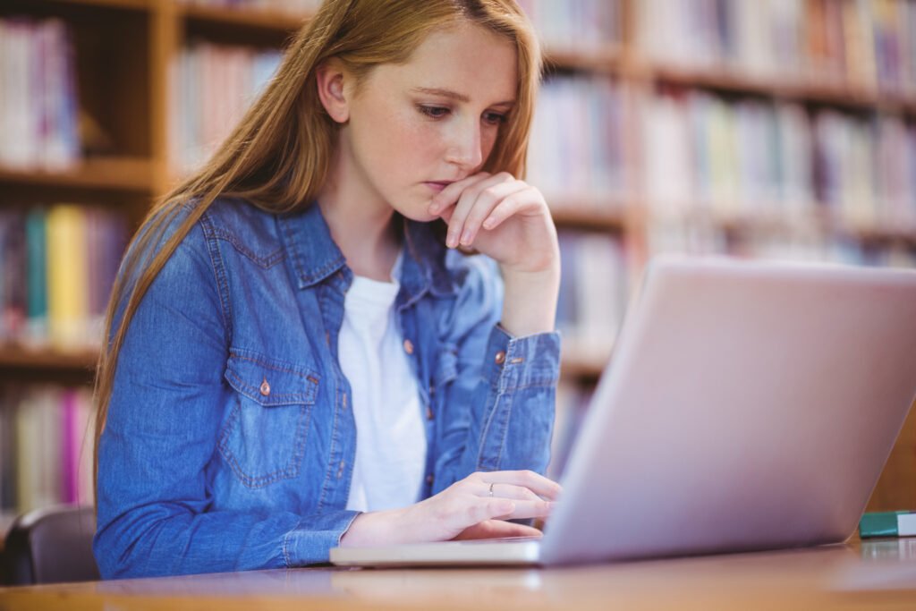 Focused student using laptop in library