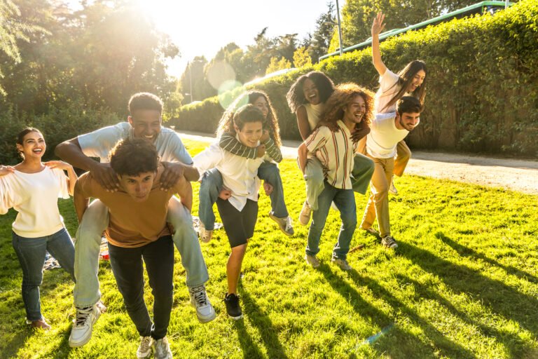 Happy friends piggybacking in a sunny park, enjoying their time together