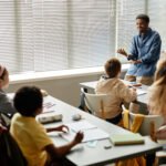 Smiling African American Teacher Talking to Children in Classroom at Primary School